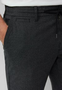 Szare spodnie w kratę o subtelnym wzorze kratki, z przednią kieszenią oraz elastycznym pasem z troczkiem.