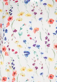 Lilleline pluus valgel taustal, kus on rohkelt värvipunkte punastes, kollastes, lillades ja sinistes lilleedes.