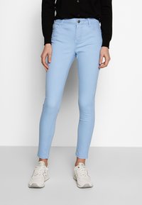 Ljusblå skinny jeans i bomullsblandning med fem fickor, framknäppning och subtila sömdetaljer. Kombinerat med vita sneakers.