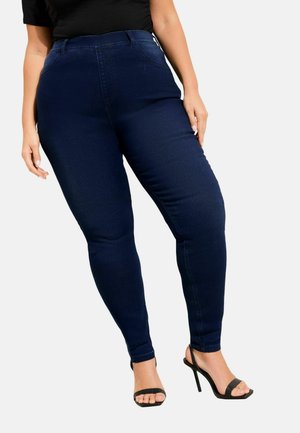 Blugi skinny decoloriți bleumarin, cu talie înaltă, din denim cu textură netedă și design cu cinci buzunare, asortați cu sandale negre cu barete și toc înalt.