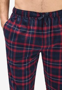 Röd och marinblå rutiga pyjamasbyxor med elastisk midja, snörning och sidofickor, med ett lätt tyg och rutmönster.