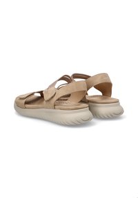 Sandalias beige con un diseño de correa texturizada, plantilla acolchada y suela blanca gruesa. Cierre de velcro para un ajuste seguro. Acabado en material suave.