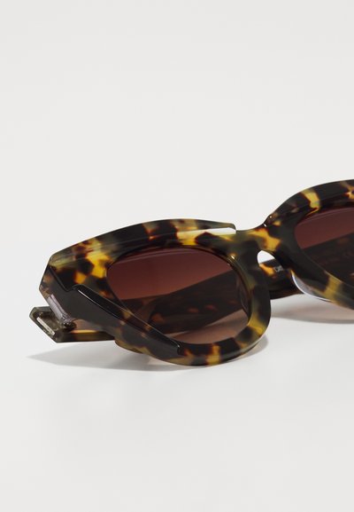 Tortoiseshell sunglasses with a geometric frame, dark brown lenses, and distinct texture patterns. Features angled arms for secure fit.