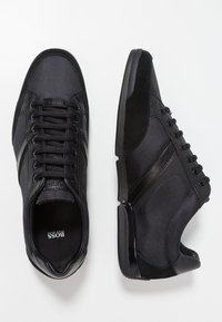 Czarne sneakersy z połączenia gładkiej skóry i teksturowanej siateczki. Okrągły czubek, sznurowany design oraz subtelne akcenty po bokach. Gumowe podeszwy.