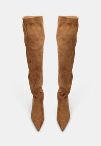 Bruna mockaskinn över knäna stövlar med spetsig tå och åtsittande design, med slät textur och utan synlig hårdvara eller dekorationer.