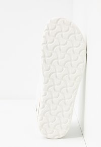 Suola di scarpa in gomma bianca con un motivo zigzag testurizzato e logo impresso, di forma curvata e finitura liscia.