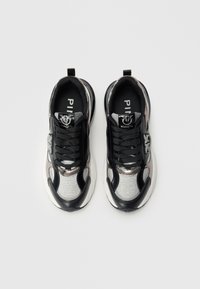 Zwarte en zilveren sneakers met een gestructureerde bovenkant, vetersluiting en logo op de tong; gladde en metallic accenten aan de zijkanten.