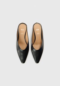 Czarne skórzane buty wsuwane z szpiczastym noskiem i odkrytą piętą. Charakteryzują się gładką fakturą i minimalistycznym designem, oznaczone napisem "BOSS".