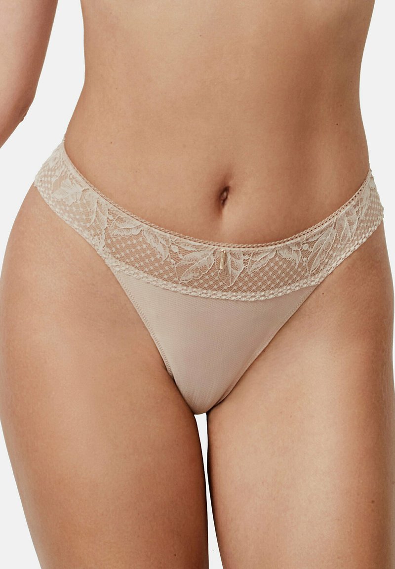 Beige kanten string met een doorzichtig mesh lichaam, bloemige kanten tailleband en delicate accenten, ontworpen voor een soepele pasvorm en comfort.