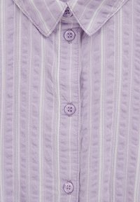 Fialová košeľa s vertikálnymi bielymi pruhmi, textúrovanou tkaninou, špicatým golierom a štyrmi viditeľnými fialovými gombíkmi na prednej strane.