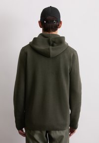 Olive green hooded sweatshirt with ribbed texture and kangaroo pocket, featuring a relaxed fit and a back view. Pairing with matching pants.