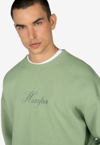 Felpa verde in cotone con colletto a girocollo, caratterizzata da ricamo "Harper" in corsivo sul davanti. Tessuto morbido e vestibilità comoda.