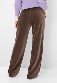 Bruine wijde corduroy broek met een zachte textuur en verticale ribbels, voorzien van zijzakken en een relaxte pasvorm voor comfortabel dragen.