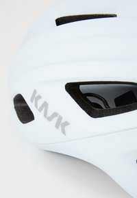 Gros plan sur un casque de cyclisme KASK bleu clair, avec des ouvertures de ventilation et le logo de la marque affiché en argent.