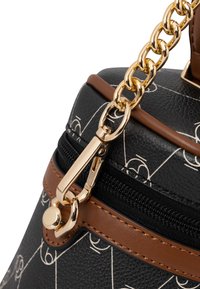 Zwarte handtas met textuur, voorzien van een wit geometrisch patroon, bruine accenten en een gouden kettingband. Voorzien van een ritssluiting en gedetailleerde hardware.