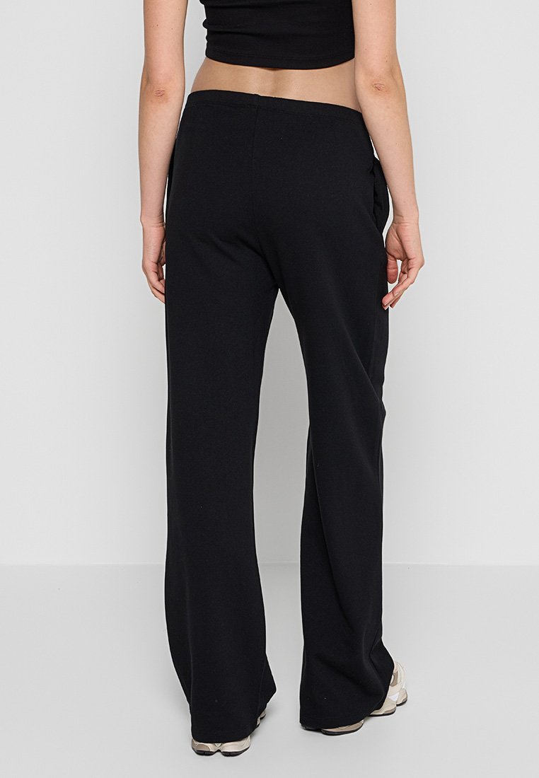 Pantalones de pierna ancha negros, confeccionados con una tela suave, que cuentan con una cintura alta y bolsillos traseros para mayor funcionalidad.