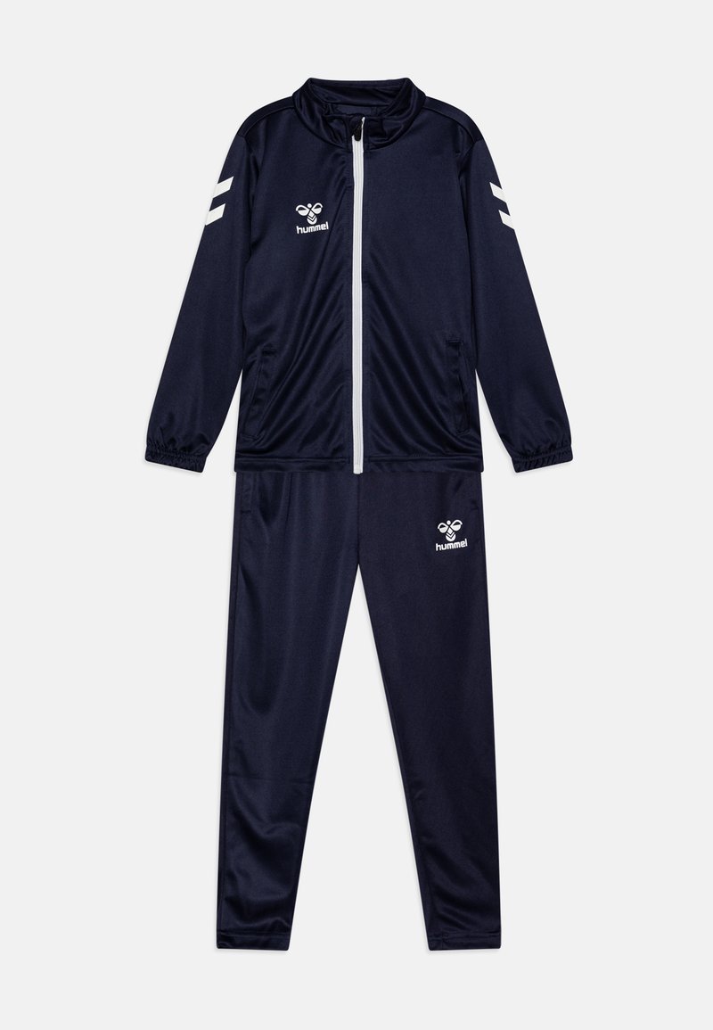 Σκούρο μπλε αθλητική φόρμα από λεία υφή, περιλαμβάνει μπουφάν με φερμουάρ και παντελόνια με ελαστική μέση. Λευκό λογότυπο και λεπτομέρειες ρίγες στους ώμους.