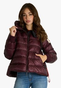 Giacca imbottita bordeaux con trapuntatura orizzontale, cappuccio, chiusura con cerniera, polsini a coste e tasche laterali. Texture lucida con dettagli neri a contrasto.