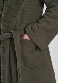 Olivgrüner Bademantel aus strukturiertem Stoff mit einem mit Fell gefütterten Kragen, beltem Bund und seitlichen Taschen. Verfügt über ein gemütliches, warmes Design.