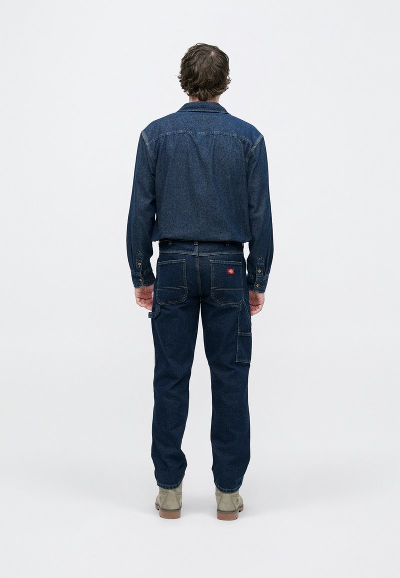 Denim shirt and pants set in a dark wash. Shirt features a button-down collar and chest pockets. Pants have back pockets and a side tool pocket.