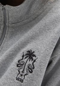 Gray sweatshirt made of soft material featuring a black embroidered design with a palm tree and snakes, along with a "VANS" logo.