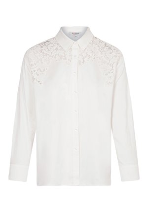Camicia bianca con bottone, caratterizzata da dettagli in pizzo ricamato sulla spalla, colletto strutturato e maniche lunghe, realizzata in tessuto liscio.