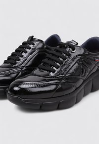 Baskets en cuir verni noir avec une finition lisse et brillante. Bout arrondi, semelle épaisse et rembourrée, et lacets noirs. Détail de logo subtil sur le côté.