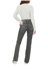 Graue ausgestellte Jeans mit mittlerer Leibhöhe und Gesäßtaschen. Kombiniert mit einem hellen Langarmoberteil. Das Material scheint Denim mit einer glatten Textur zu sein.