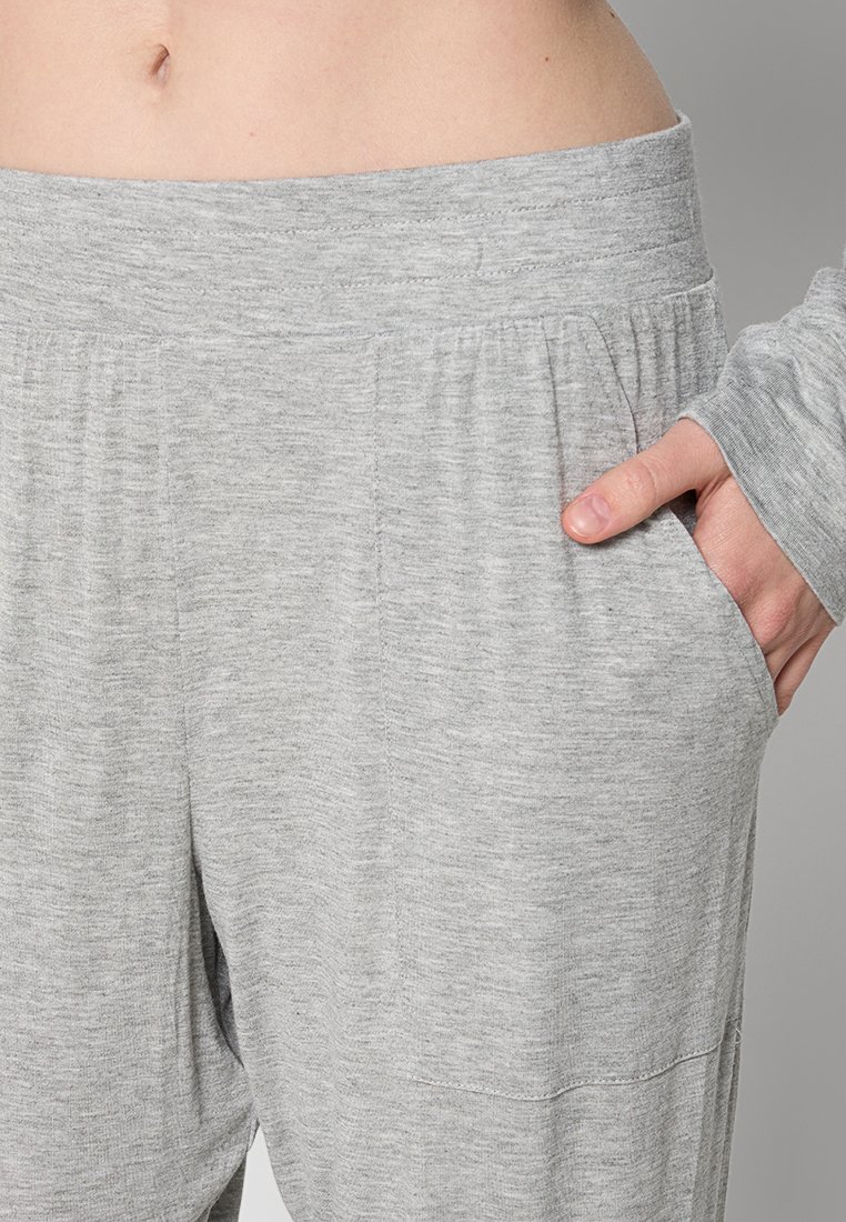 Szare spodnie dresowe z elastycznym pasem, bocznymi kieszeniami i luźnym krojem. Materiał wydaje się miękki i lekko teksturowany.