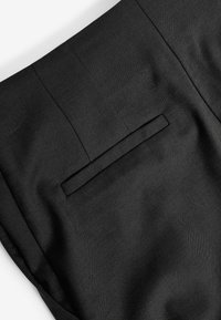 Pantalon noir sur mesure avec une texture lisse, doté d'une unique poche arrière et d'un design épuré et droit. Aucun motif ou ornement visible.