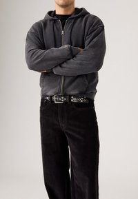 Gray zip-up hoodie with a soft texture, paired with black corduroy pants featuring a straight leg. Black belt with silver hardware accents.