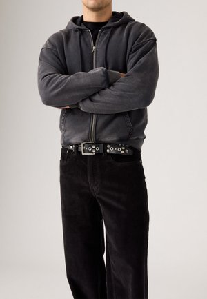 Gray zip-up hoodie with a soft texture, paired with black corduroy pants featuring a straight leg. Black belt with silver hardware accents.