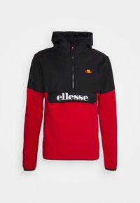 Chaqueta tipo pulóver en rojo y negro con capucha ajustable, cierre frontal con cremallera y logotipo "ellesse" en blanco. Presenta un diseño de bloques de color con un detalle de logotipo bordado.