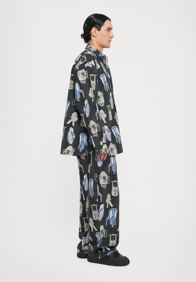 Tenue noire à motifs comprenant une variété de chaises et d'objets illustrés en gris et bleu, fabriquée à partir d'un tissu lisse, avec une coupe ample.