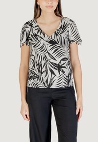 Top a maniche corte con scollo a V in un tessuto leggero caratterizzato da una stampa di foglie bianco e nero, con delicati volant sulle maniche. Abbinato a pantaloni scuri.