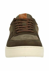 Bruine en groene sneaker met veters, voorzien van een suede afwerking en een tanleren logo patch op de tong, tegen een witte achtergrond.