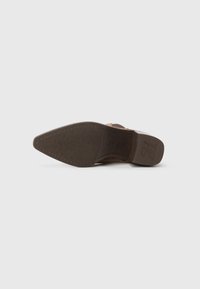 Semelle de chaussure en cuir marron présentant une forme pointue, un dessous en caoutchouc texturé pour une meilleure adhérence, et le nom de la marque "paul green" en relief.