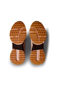 Par de zapatillas con suelas de goma marrón, medias suelas rosas y secciones de soporte marrón oscuro, vistas desde abajo sobre un fondo blanco.