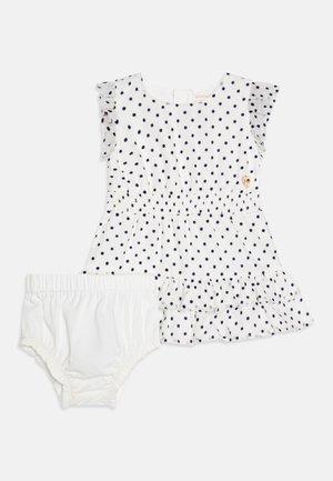 Fehér pamutruha sötétkék pöttyökkel, fodros ujjak, és réteges szoknya, párosítva egy hozzá illő fehér bugyival.