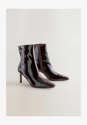 Lakované členkové čižmy s lesklou bordovou farbou, špicatou špičkou a bočným zipsom. Obsahujú ihlový opätok pre väčšiu výšku.