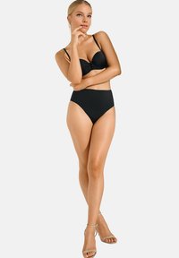 Ensemble de bikini noir comprenant un haut rembourré avec un détail torsadé et un bas taille haute. Tissu lisse avec des accents minimaux, assorti à des talons nus.