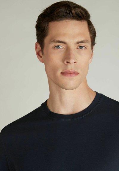 T-shirt marine à col rond en tissu doux ; silhouette cintrée avec des manches courtes et des détails de surpiqûre minimaux.