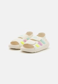 Hvite justerbare sandaler med pastelldetaljer i rosa, blå og gul. Har en teksturert overdel og en polstret, fleksibel såle.