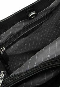 Interno di una borsa in pelle nera che mostra una fodera in tessuto grigio con sottili righe bianche e una tasca con cerniera. Dotata di chiusura a scatto metallica.