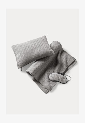 Plaid en tricot gris, coussin assorti avec fermeture éclair et masque pour les yeux. Motif texturé sur le tissu, matériau doux, sans accents supplémentaires.
