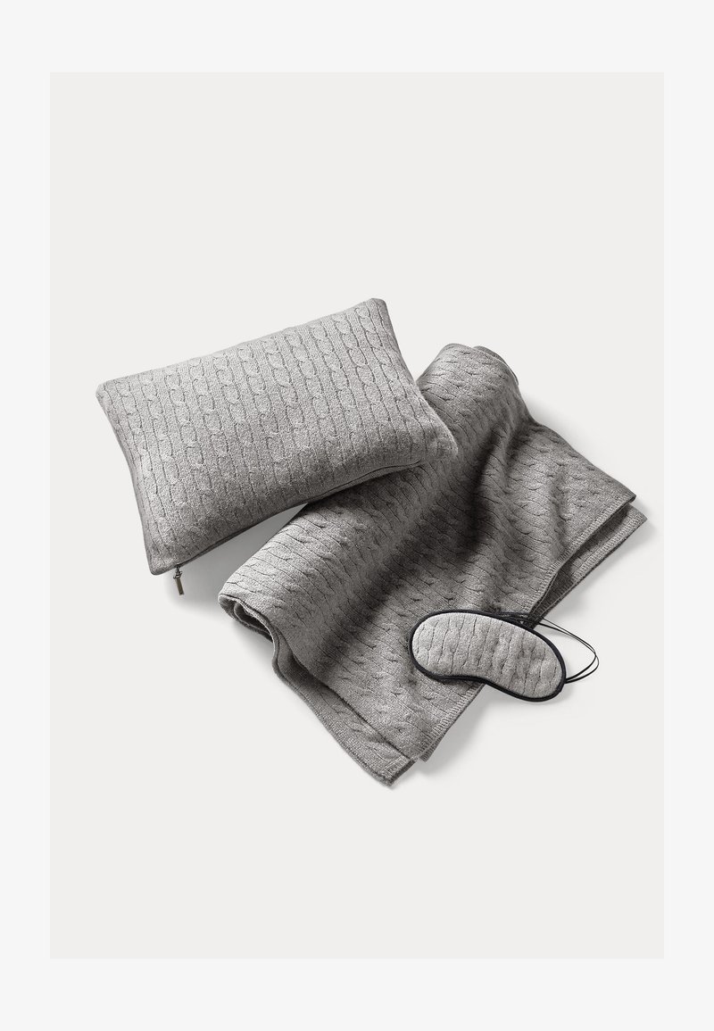 Gray knitted blanket, matching pillow with zipper, and eye mask. Textured pattern across fabric, soft material, no additional accents.