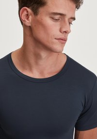 Marineblauw shirt met korte mouwen en een ronde halslijn, met een gladde textuur en een getailleerd ontwerp. Minimale stikseldetails op de kraag.