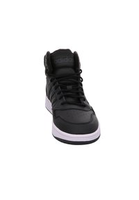 Sneaker alta nera con tomaia in pelle, dettagli texturizzati, collare imbottito, sistema di allacciatura e suola bianca. Presenta una punta perforata.