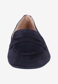 Mocassin en daim bleu foncé avec un petit talon, un bout arrondi et une bride décorative traversant l'ouverture avant.