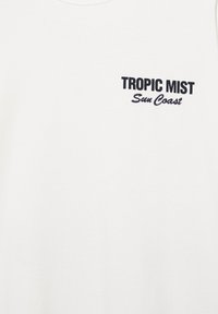 Weißes T-Shirt mit schwarzem Text „TROPIC MIST“ in Fettschrift und „Sun Coast“ in Schreibschrift auf der oberen linken Brust.